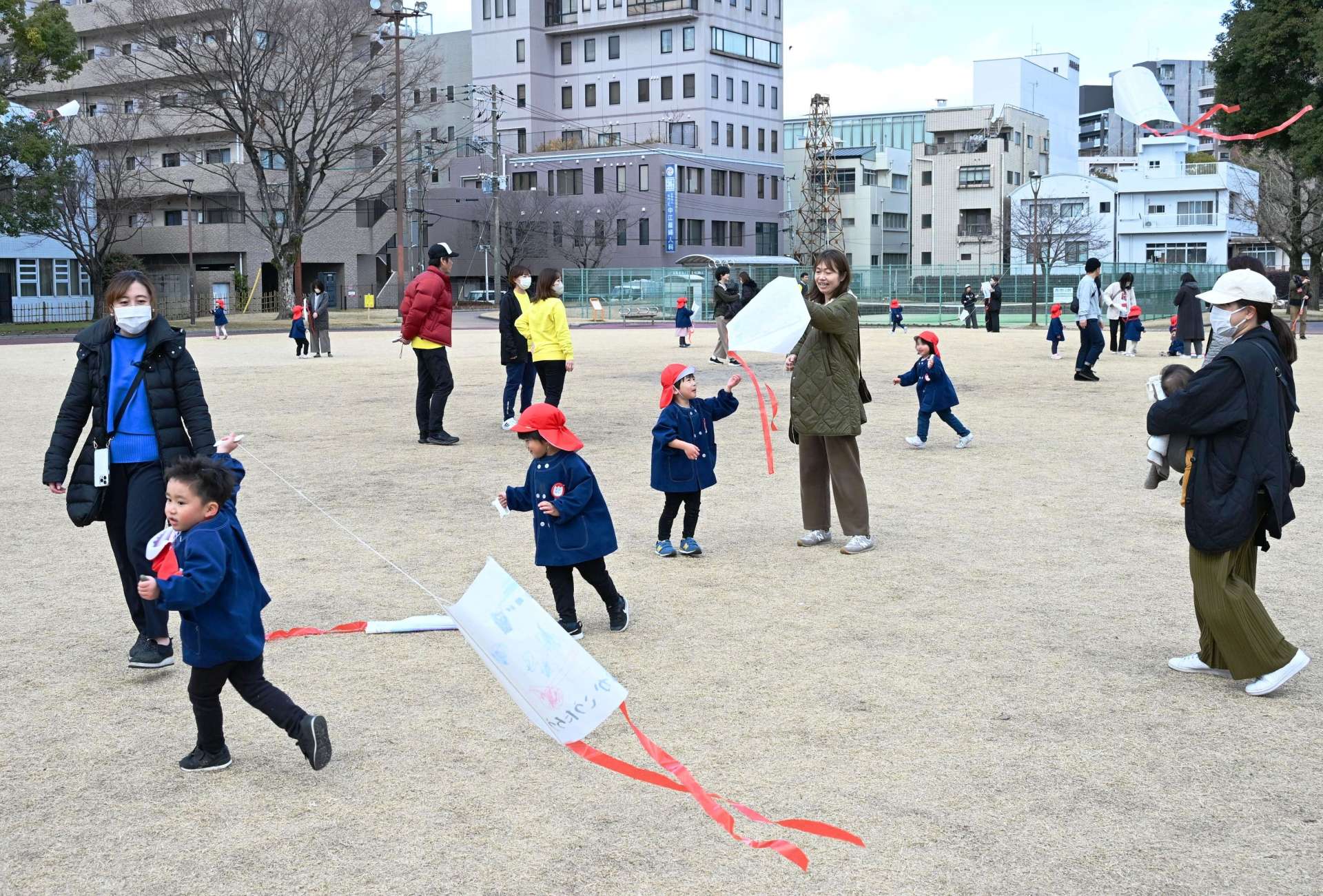 ぽかぽか陽気の中、公園でたこ揚げを楽しむ子どもたち＝２０日午後、鹿児島市中央町