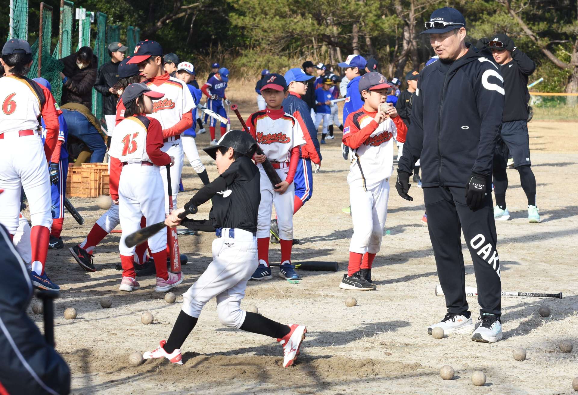 松山竜平選手（手前右）の指導を受ける小学生＝１９日、大崎町の大丸グラウンド