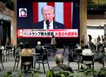 トランプ新大統領のテレビ映像を見る人たち＝２１日、鹿児島市金生町のよかど鹿児島