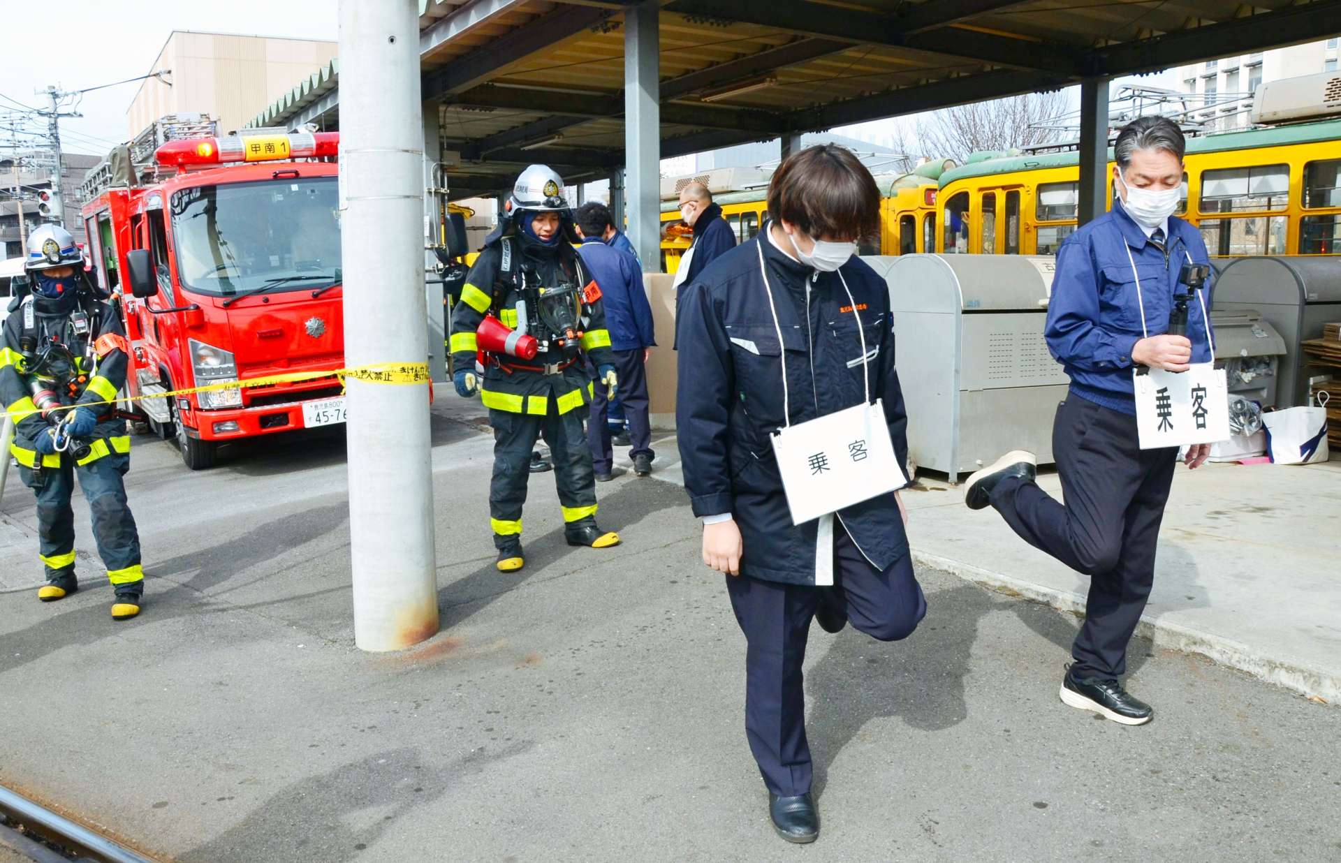 汚染物が付着していないか消防隊員に確認される乗客＝２２日、鹿児島市上荒田町の市交通局