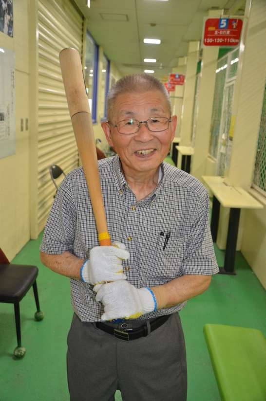 バットを持ち笑顔をみせる満山一朗さん＝鹿児島市南栄１丁目ののメテオスーパードーム、２０２３年８月６日撮影