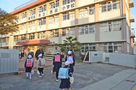 山鹿真人校長にあいさつしながら登校する児童ら＝鹿児島市薬師２丁目の西田小学校