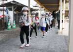 渡り廊下を静かに歩いて避難する児童＝２４日、霧島市霧島田口の霧島小学校