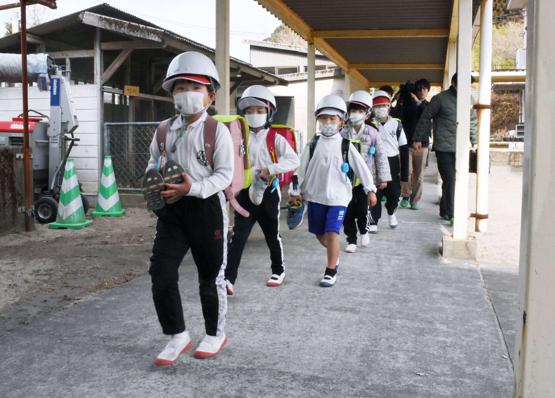 渡り廊下を静かに歩いて避難する児童＝２４日、霧島市霧島田口の霧島小学校