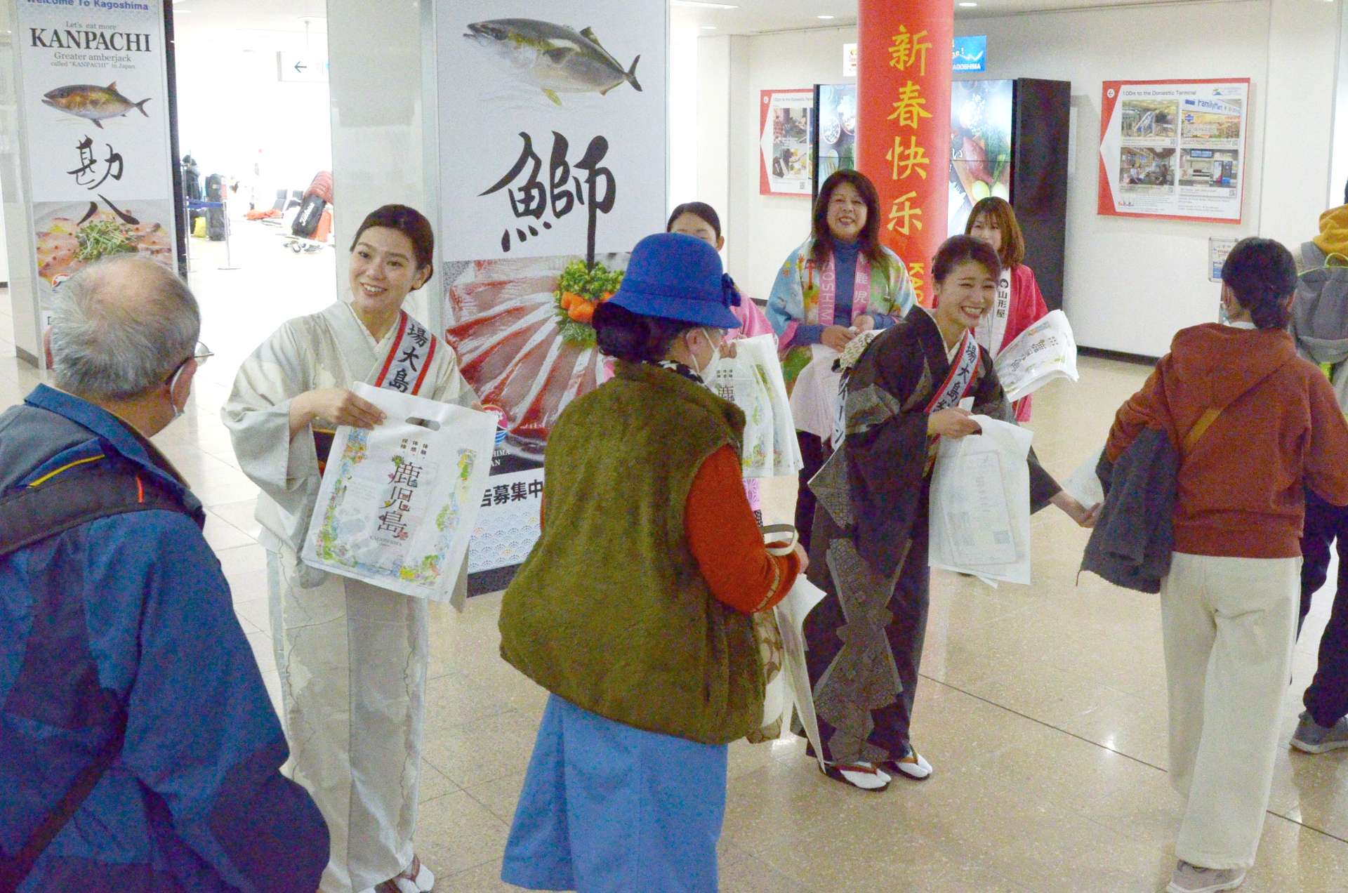 春節にあわせ来鹿した中国客を出迎える大島紬クイーンら＝２５日午後１時ごろ、霧島市の鹿児島空港国際線ターミナル