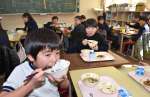 贈られた新米をおいしそうに頬張る児童＝湧水町恒次の轟小学校