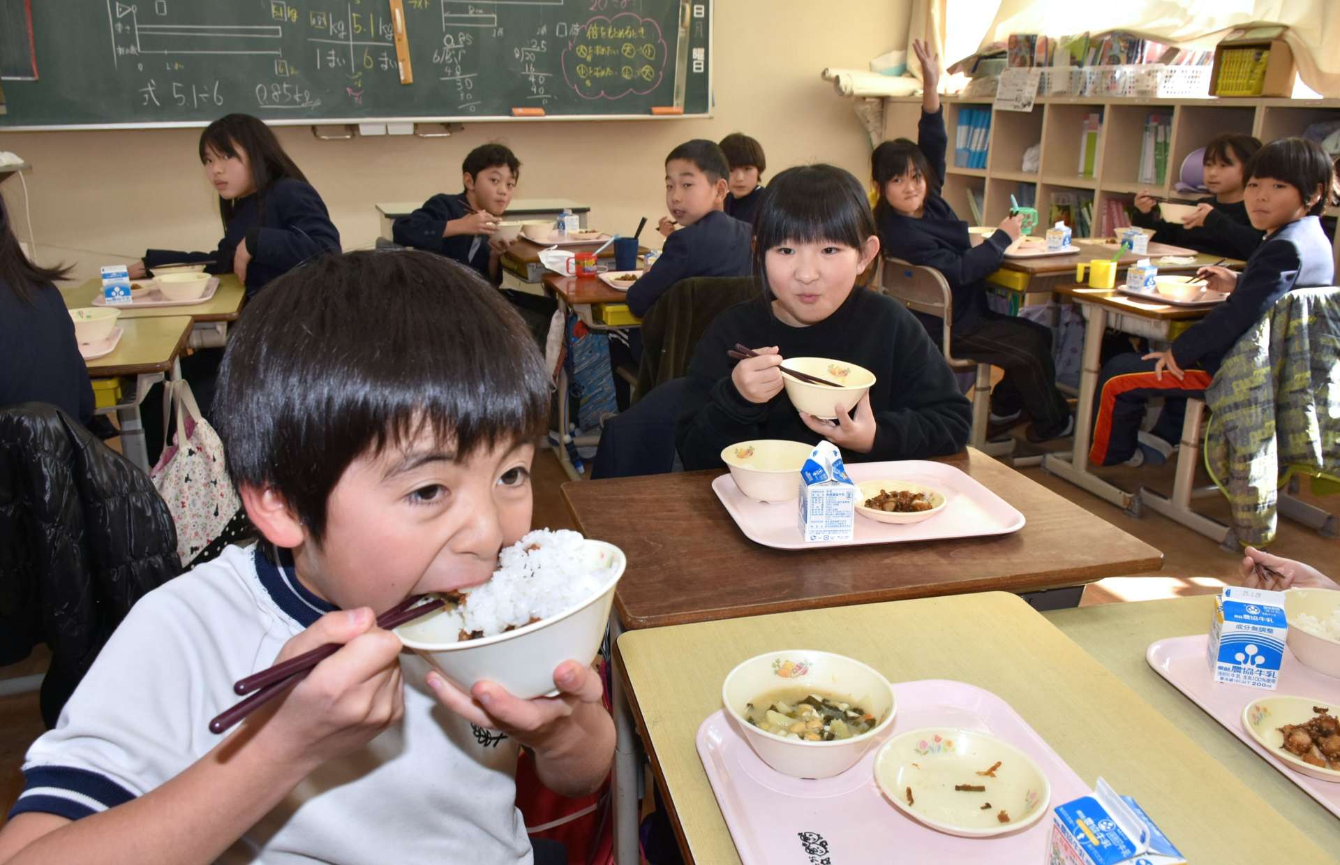 贈られた新米をおいしそうに頬張る児童＝湧水町恒次の轟小学校