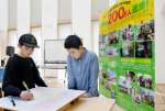 利用者２００万人達成のパネル近くでメッセージを書き込む子どもたち＝鹿児島市のかごしま環境未来館