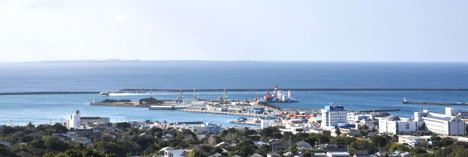 高台から望む西之表市街地と市役所（右下）。十数キロ先の水平線に馬毛島が見える＝２６日、同市
