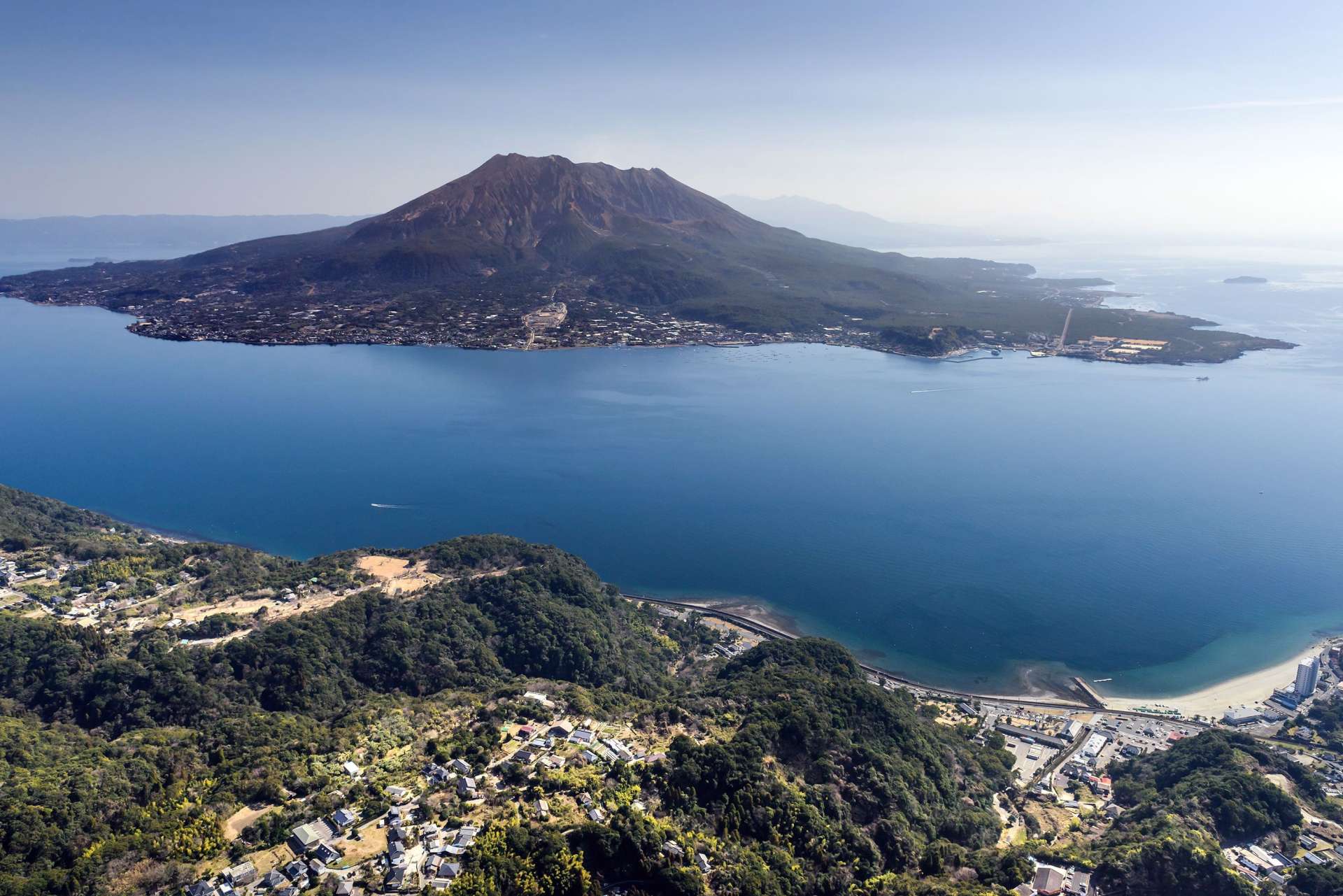 上空から望む桜島と鹿児島湾（鹿児島市提供）