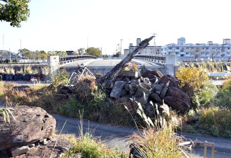 〈関連〉買収が難航している右岸側の土地。石や木が確認でき、奥には完成した橋が見える＝いちき串木野市平江
