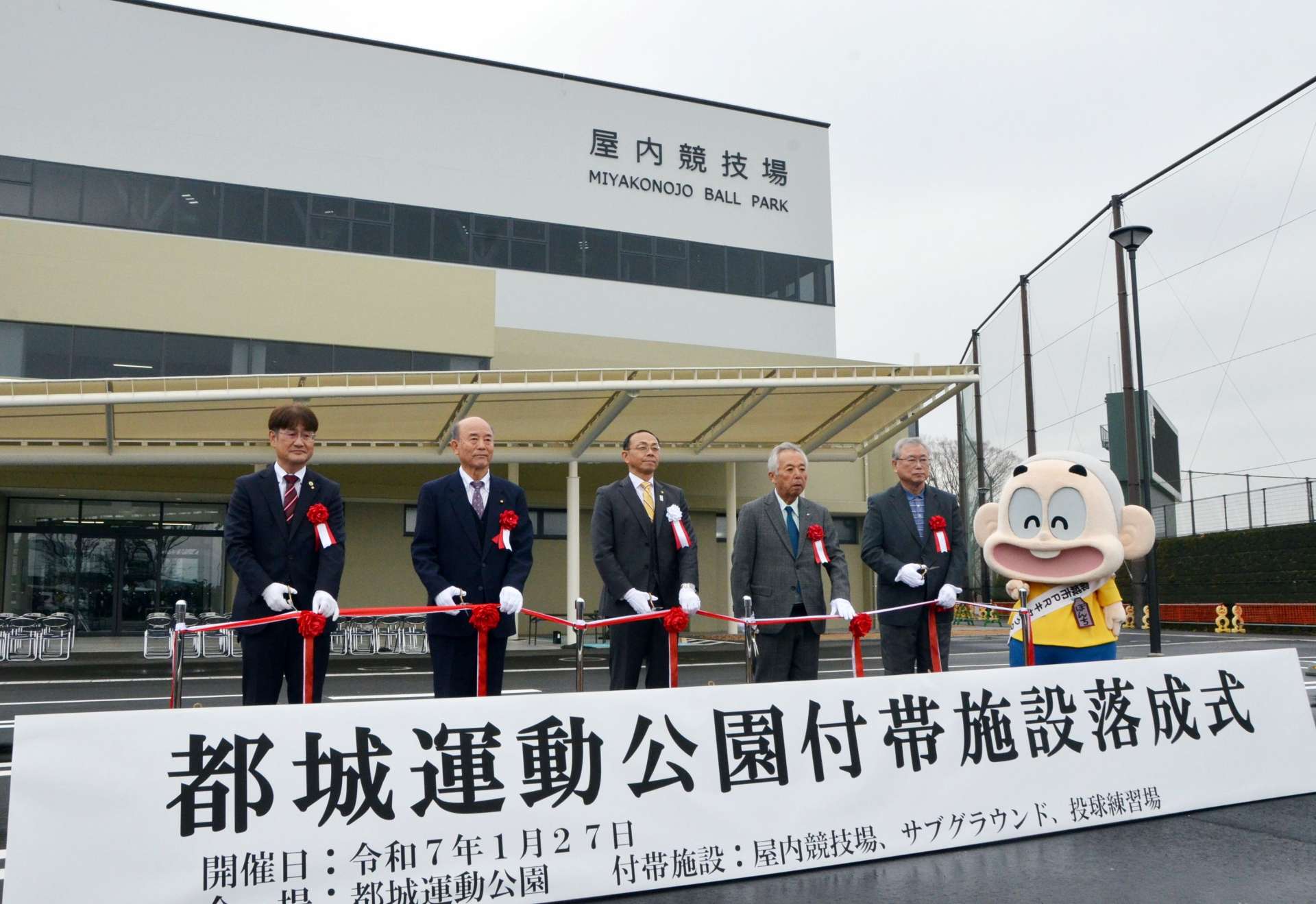 新築された屋内競技場前でテープカットする関係者＝２７日、都城市妻ケ丘町