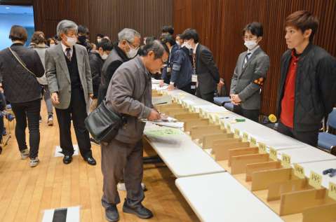 目当ての品に札を入れる来場者＝３０日、鹿児島市のカクイックス交流センター