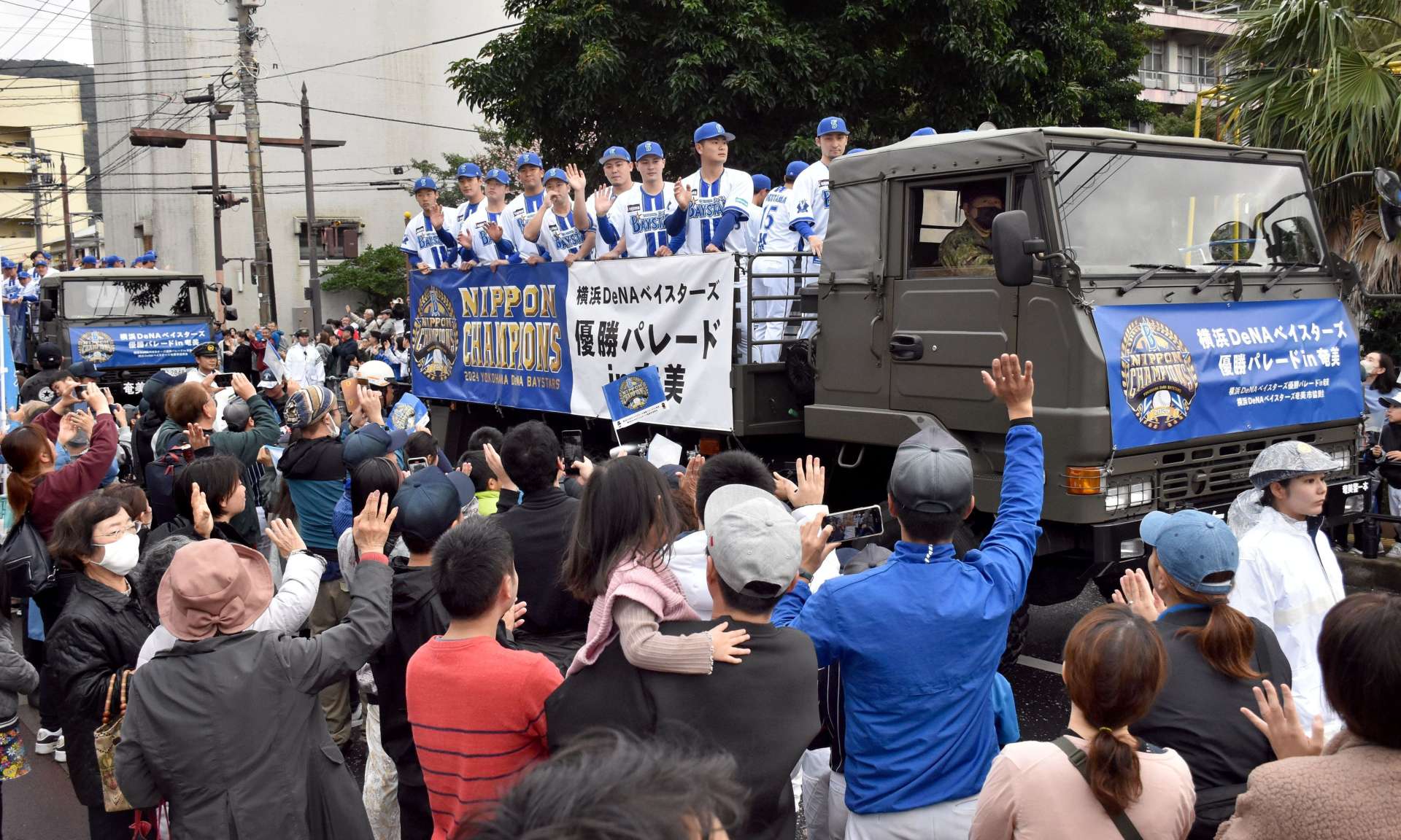 沿道の市民らに手を振る選手＝１日、奄美市名瀬