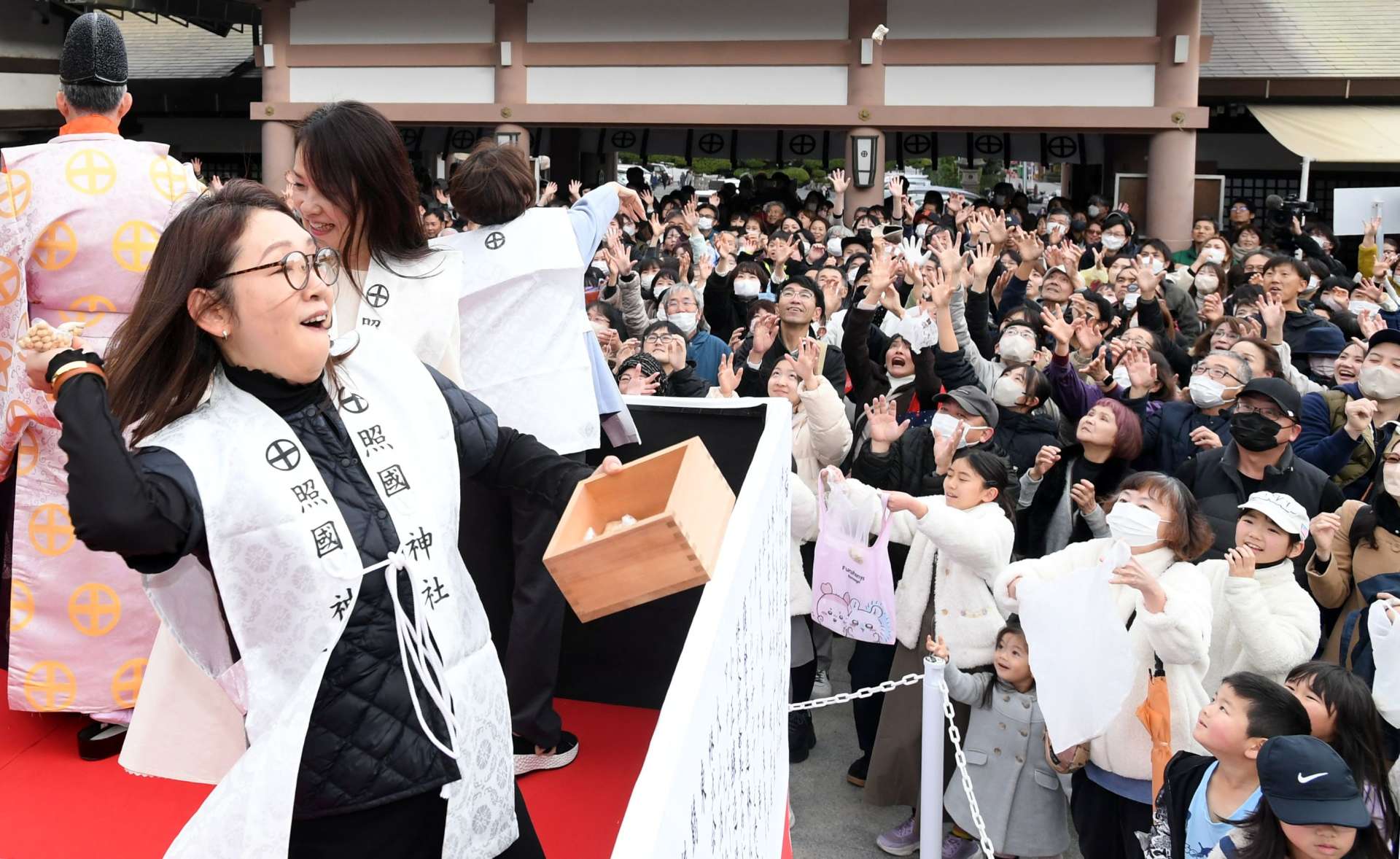 豆をまく人に向かって手を伸ばす参拝客＝２日、鹿児島市の照国神社