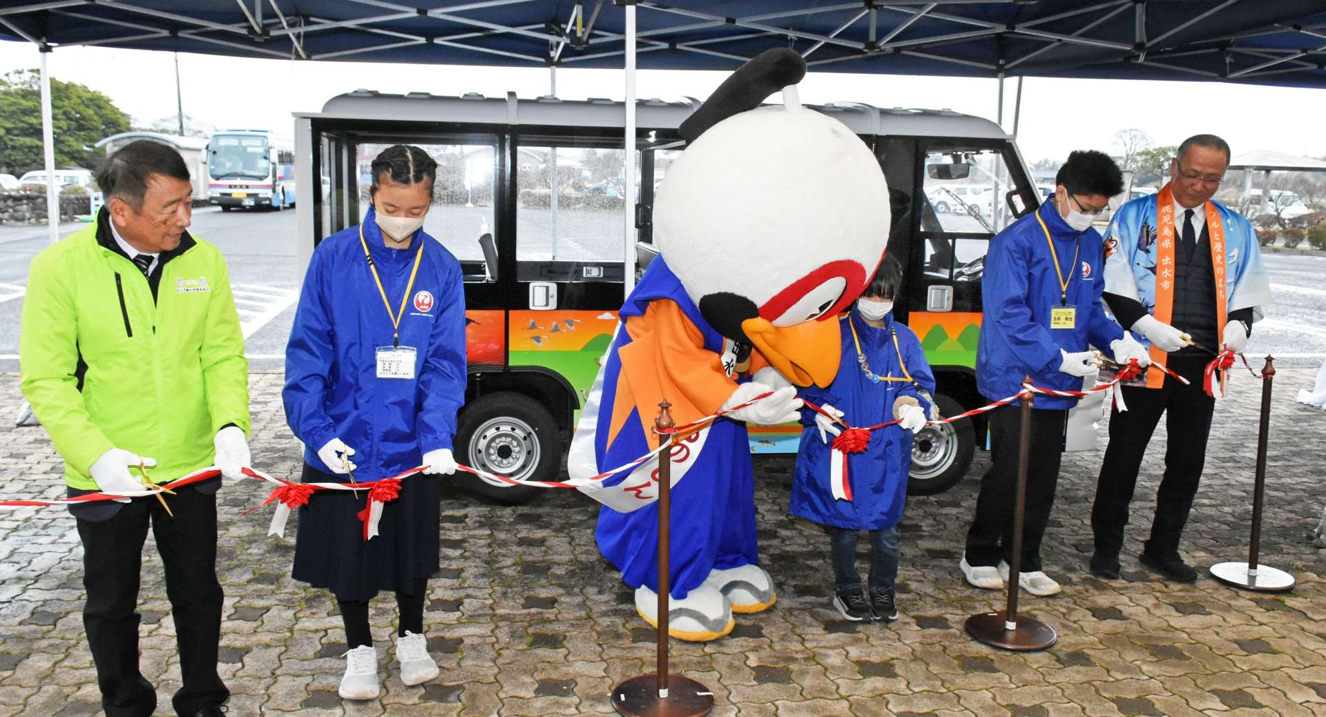 「つるのしん号」導入をテープカットで祝う市や学校関係者＝１日、出水市荘