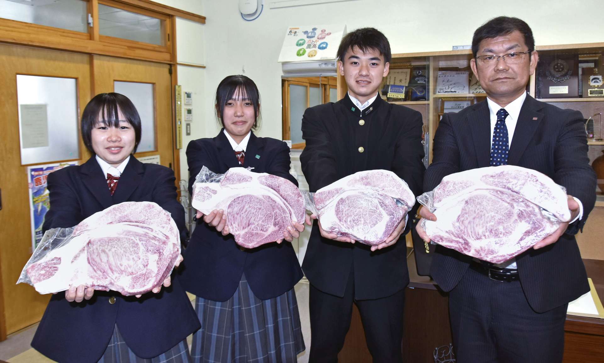 〈関連＝これが日本一に輝いた肉か…〉ロース肉を贈呈するスターゼン鹿児島営業所の神川博文所長（右）と受け取る鹿屋農業高校の生徒＝鹿屋市の同校