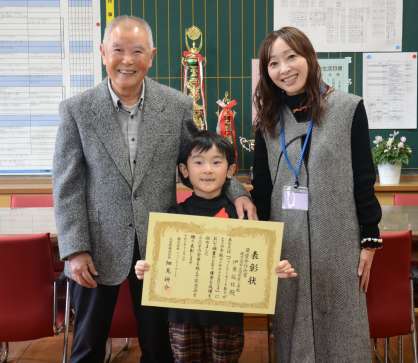 九州・沖縄ブロック低学年部門の最優秀作品賞に選ばれた伊東拓杜さん（中央）と、祖父・鶴安行さん（左）、母友紀子さん＝鹿児島市の西紫原小学校