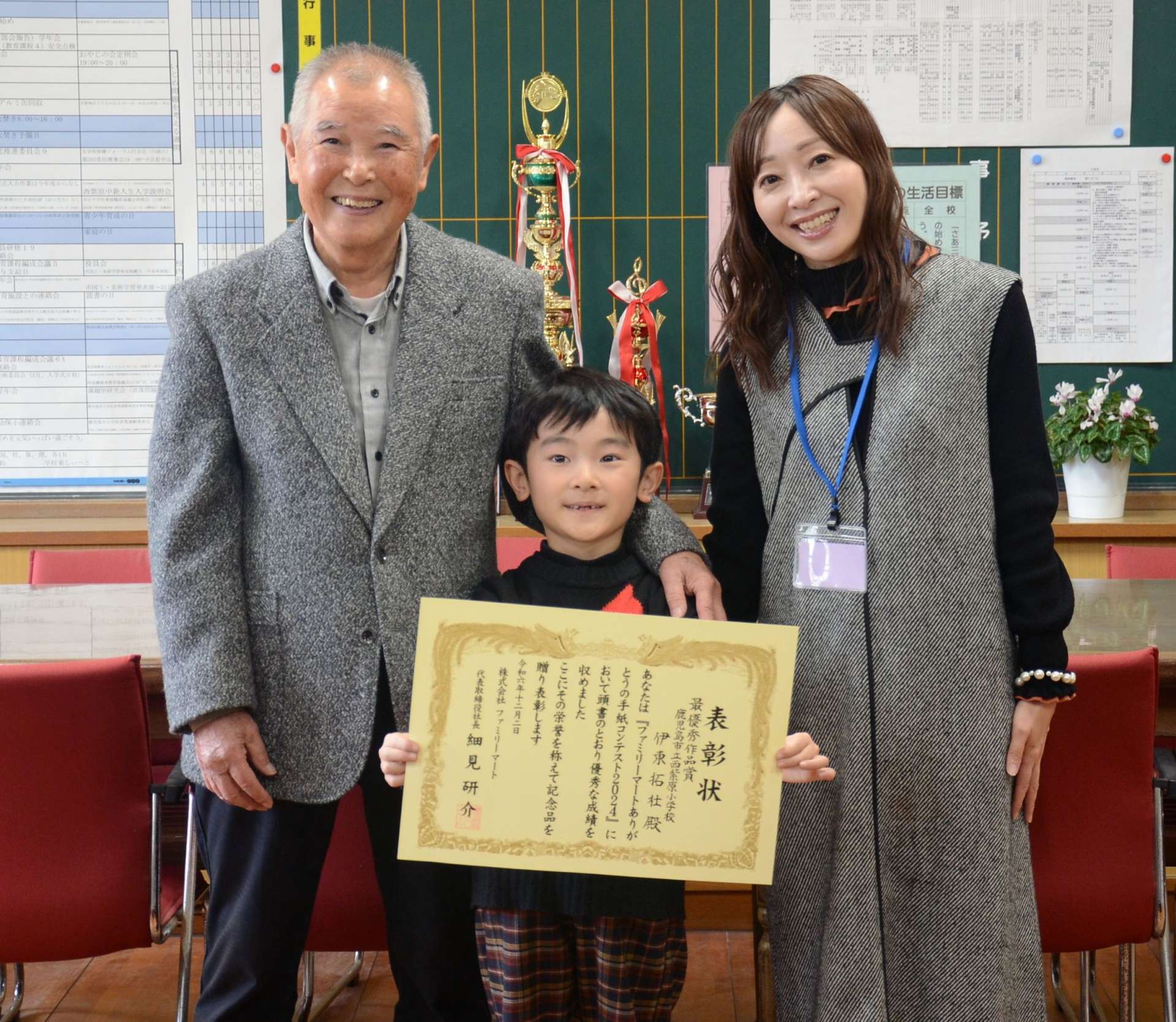九州・沖縄ブロック低学年部門の最優秀作品賞に選ばれた伊東拓杜さん（中央）と、祖父・鶴安行さん（左）、母友紀子さん＝鹿児島市の西紫原小学校