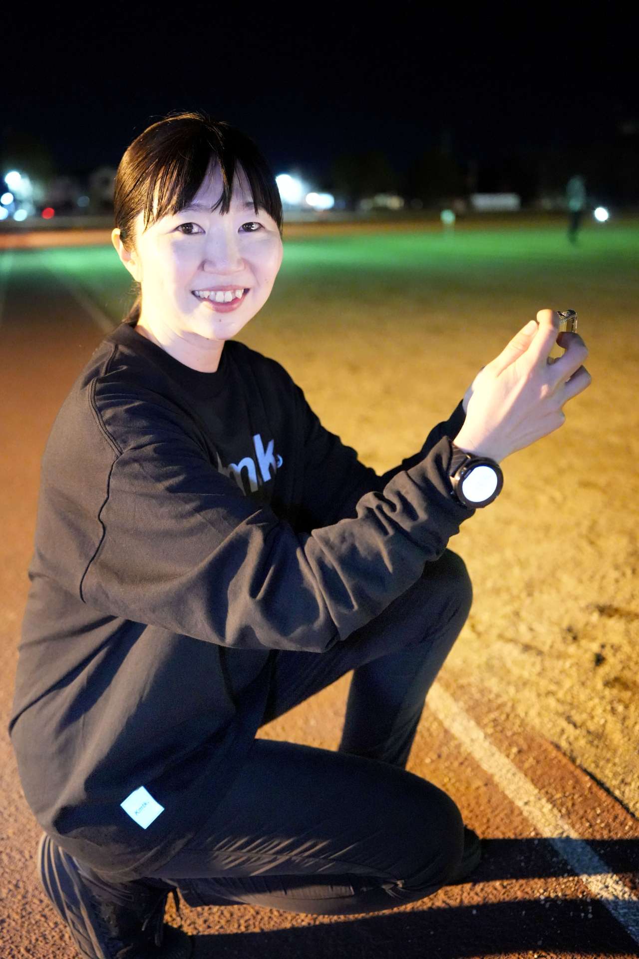 練習する選手をスマートフォンで撮影する吉原朗子さん＝鹿屋運動公園陸上競技場