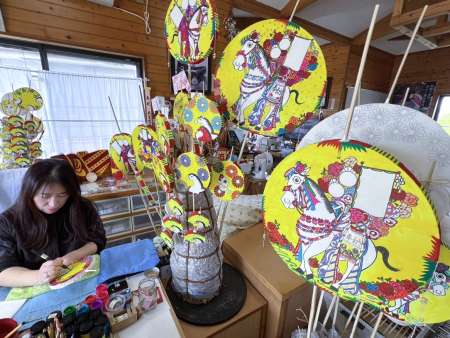 初午祭に向けてポンパチの絵付け作業に追われる森山かおりさん＝４日、霧島市隼人町内山田３丁目
