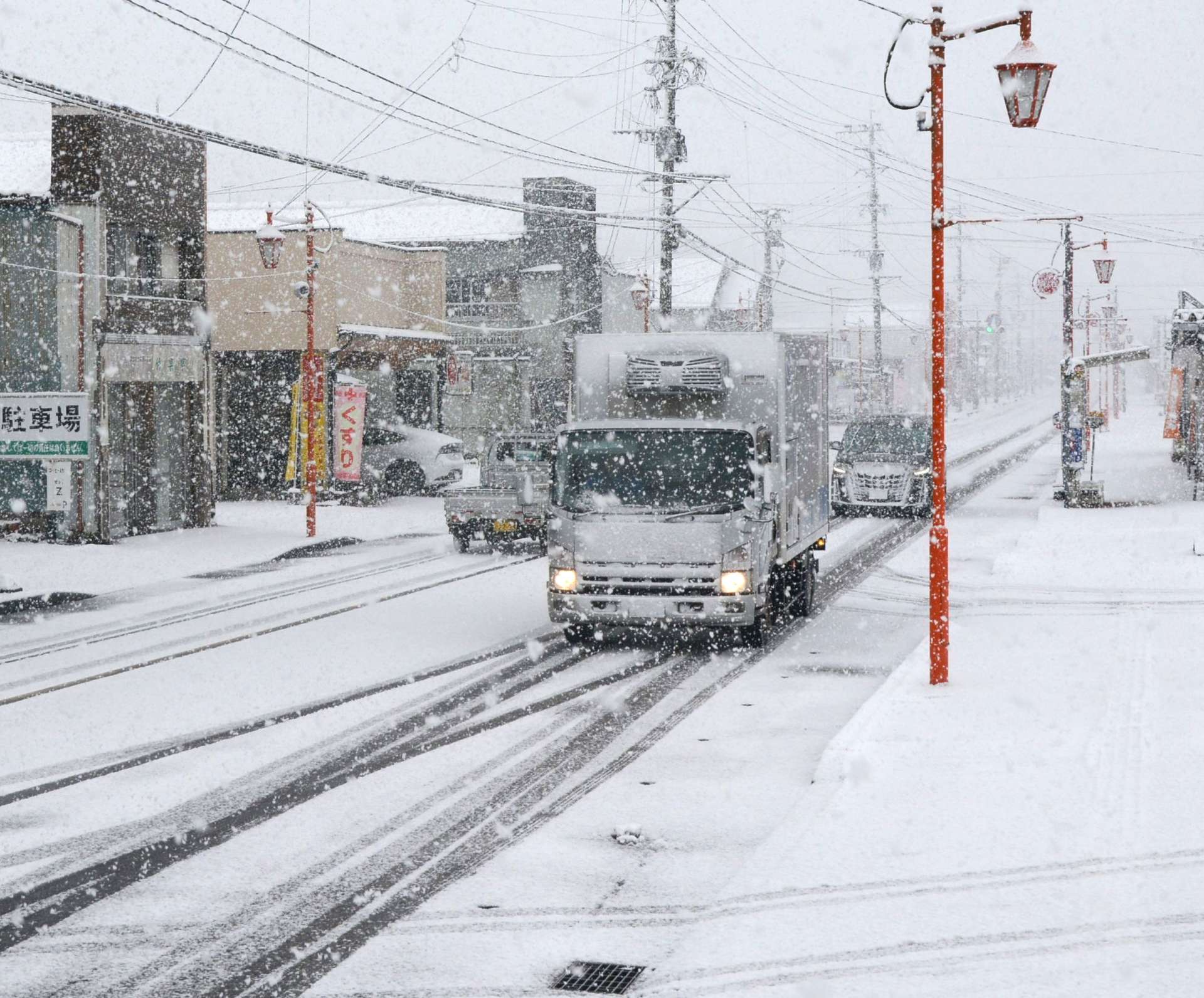 降雪で視界が悪くライトを付けた車が走るさつま町中心部＝５日、さつま町宮之城屋地