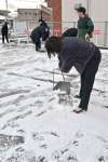 駐車場の雪かきに追われる銀行職員＝５日午前８時１２分、鹿児島市吉野町