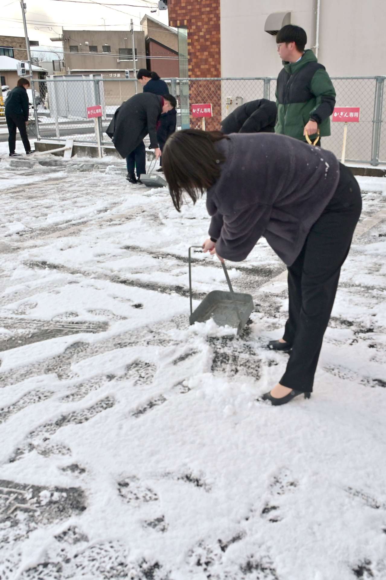 駐車場の雪かきに追われる銀行職員＝５日午前８時１２分、鹿児島市吉野町