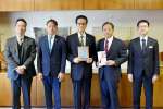 鹿屋市に１０万円を寄付した金沢幸一社長（中央）と中西茂市長（中央右）＝６日、鹿屋市役所