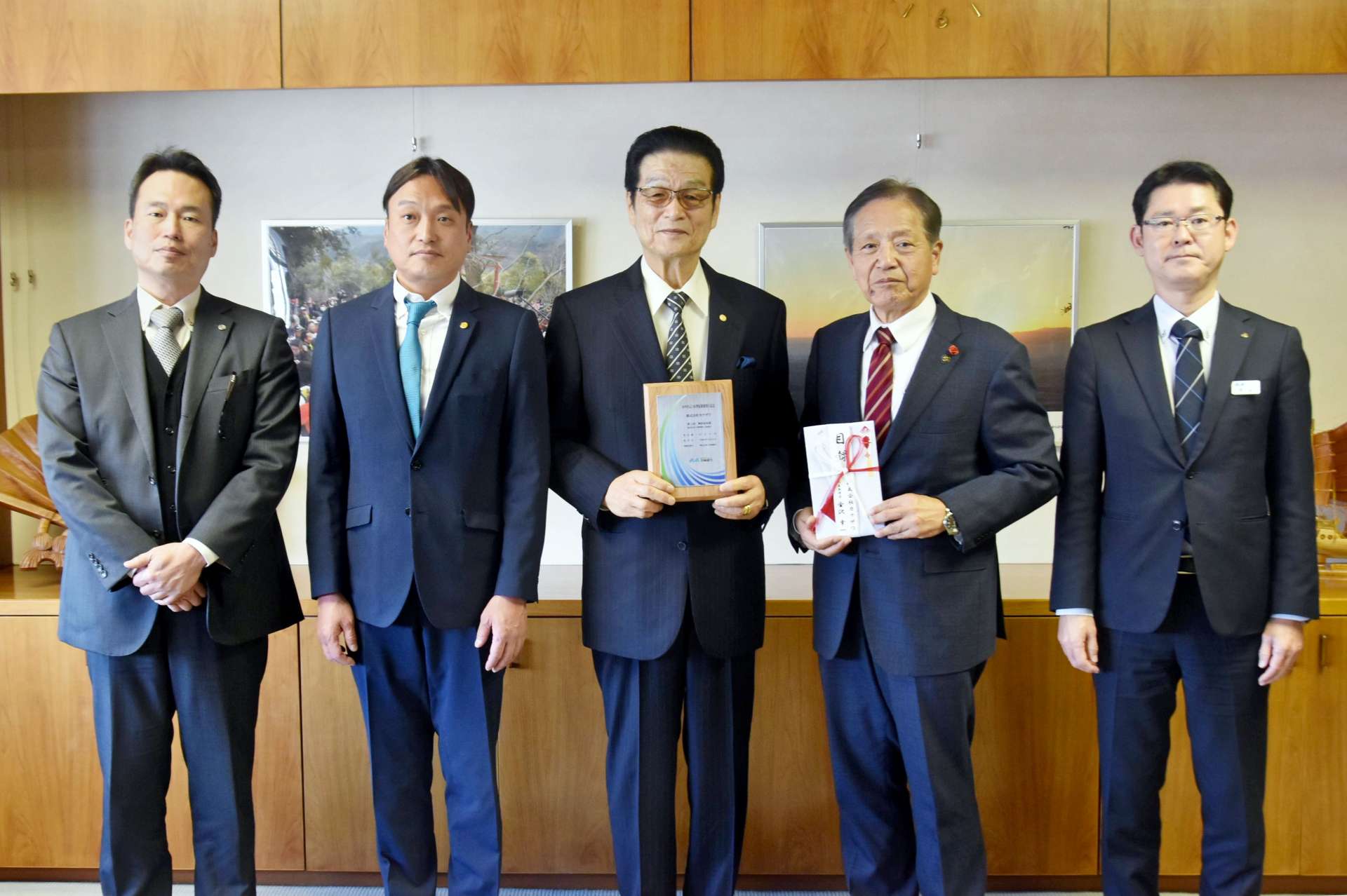 鹿屋市に１０万円を寄付した金沢幸一社長（中央）と中西茂市長（中央右）＝６日、鹿屋市役所