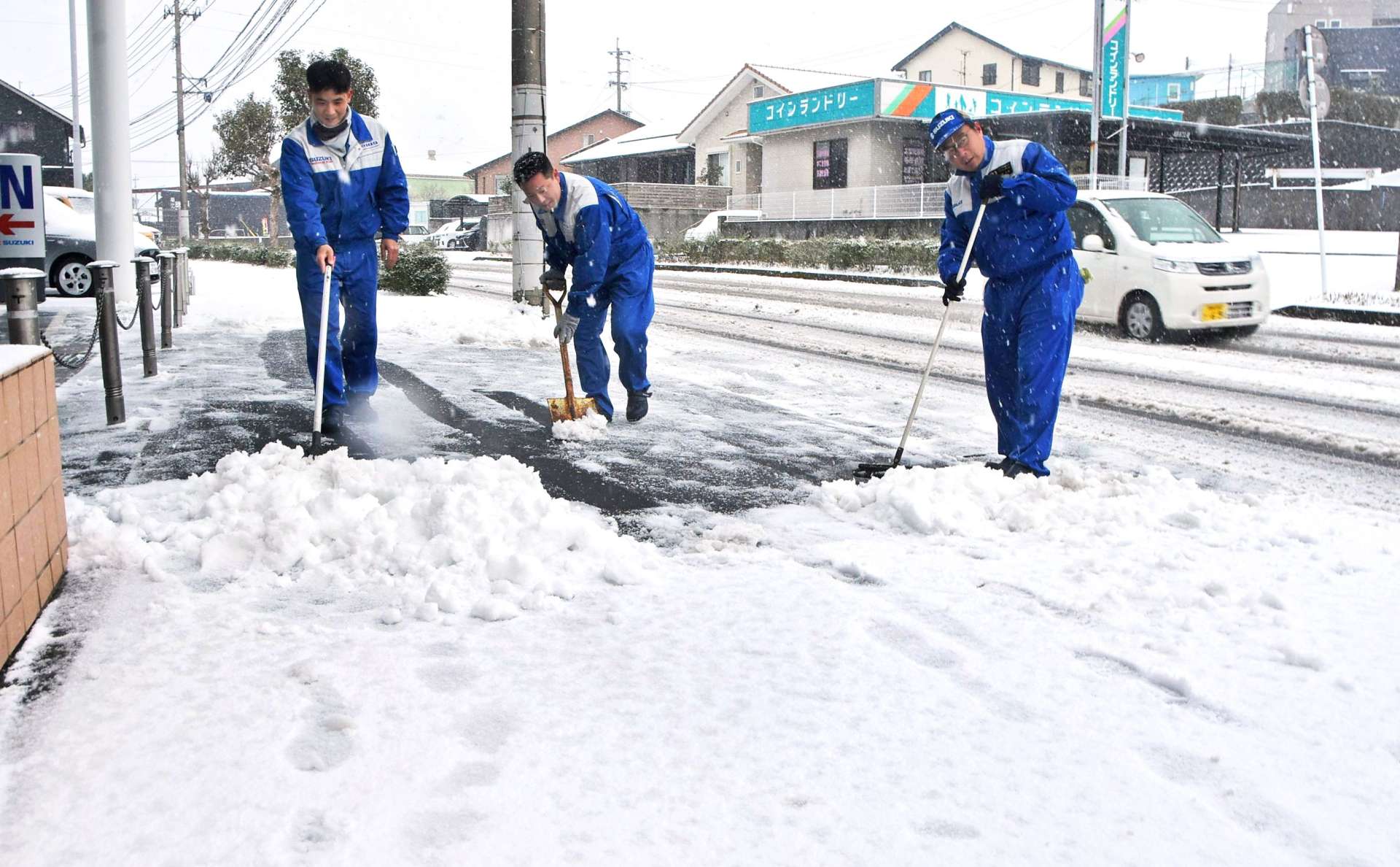 会社前の歩道の雪かきをする従業員＝８日午前、南さつま市加世田