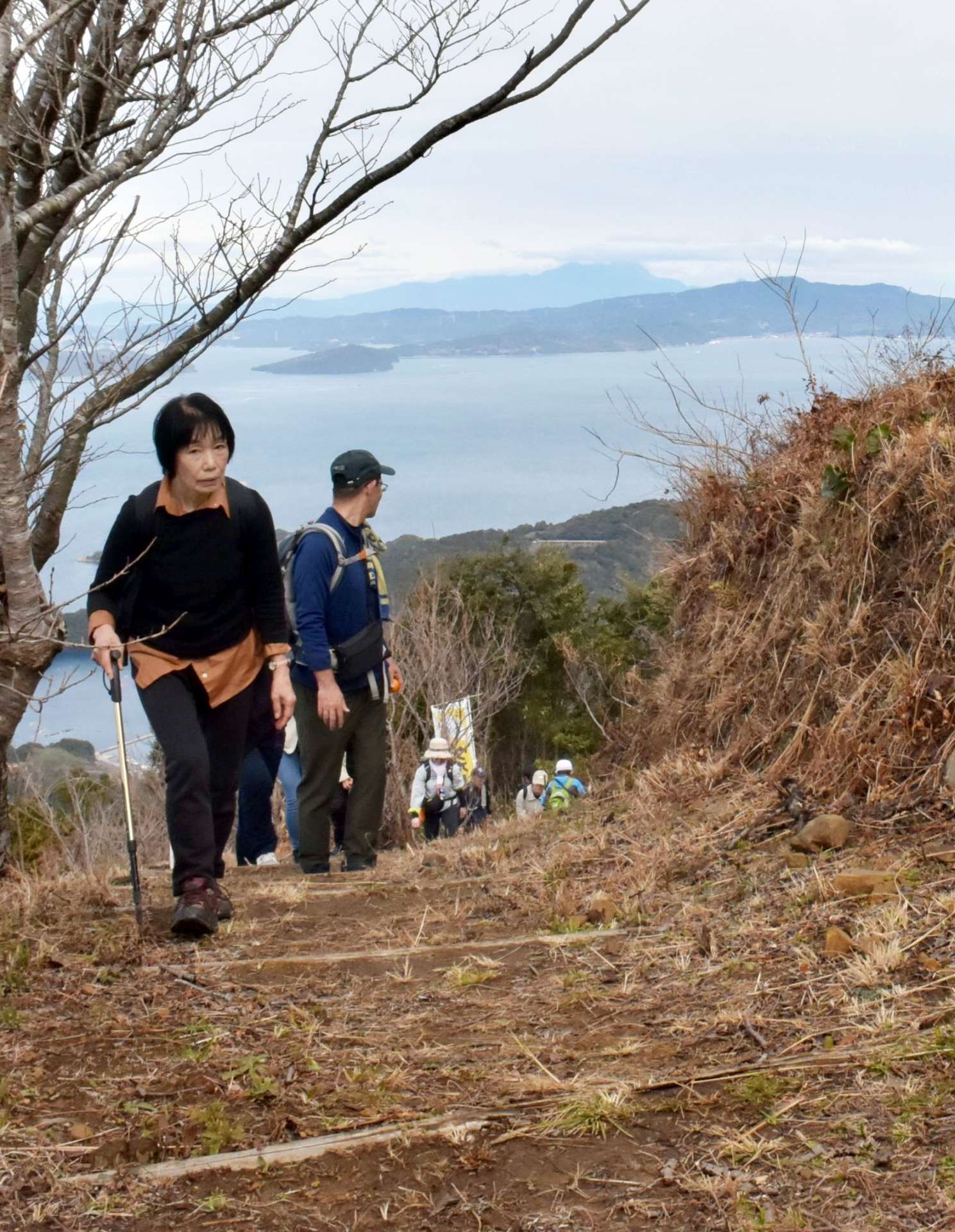 天草諸島や雲仙普賢岳を望む山道を登る獅子島ウオーク参加者＝長島町獅子島の七郎山