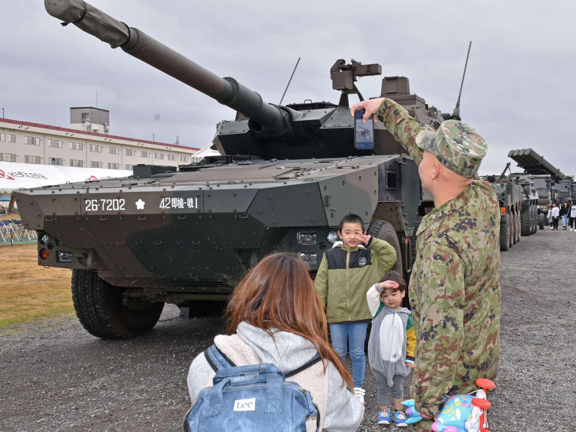 展示された自衛隊の機動戦闘車の前で写真を撮る家族＝薩摩川内市の陸上自衛隊川内駐屯地
