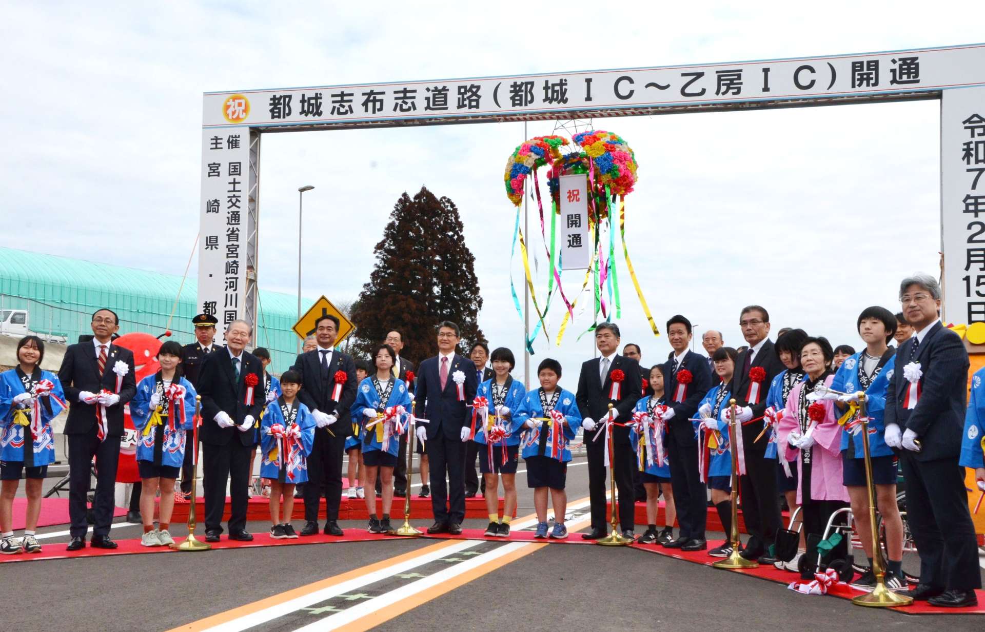 テープカットとくす玉割りを行って都城志布志道路・乙房ＩＣ－都城ＩＣの開通を祝う関係者＝１５日、都城市乙房町