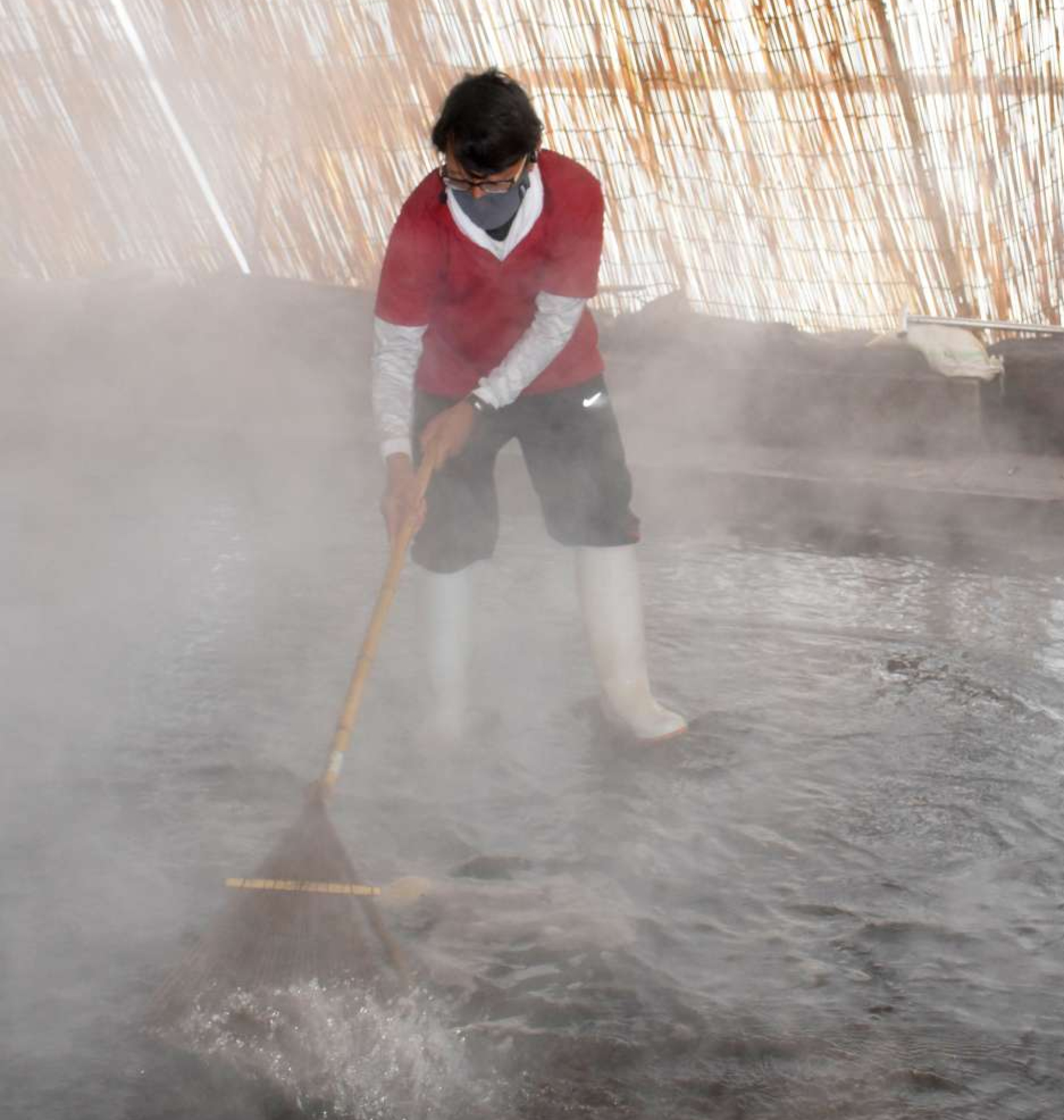 砂浴場の消毒作業をこなす加藤義人さん＝指宿市の砂むし会館砂楽