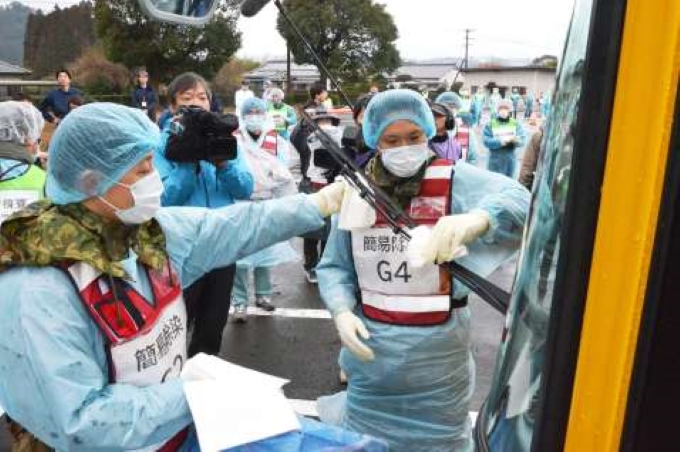 原子力総合防災訓練で避難バスを除染する検査所のスタッフら＝１６日、姶良市の県森林技術総合センター
