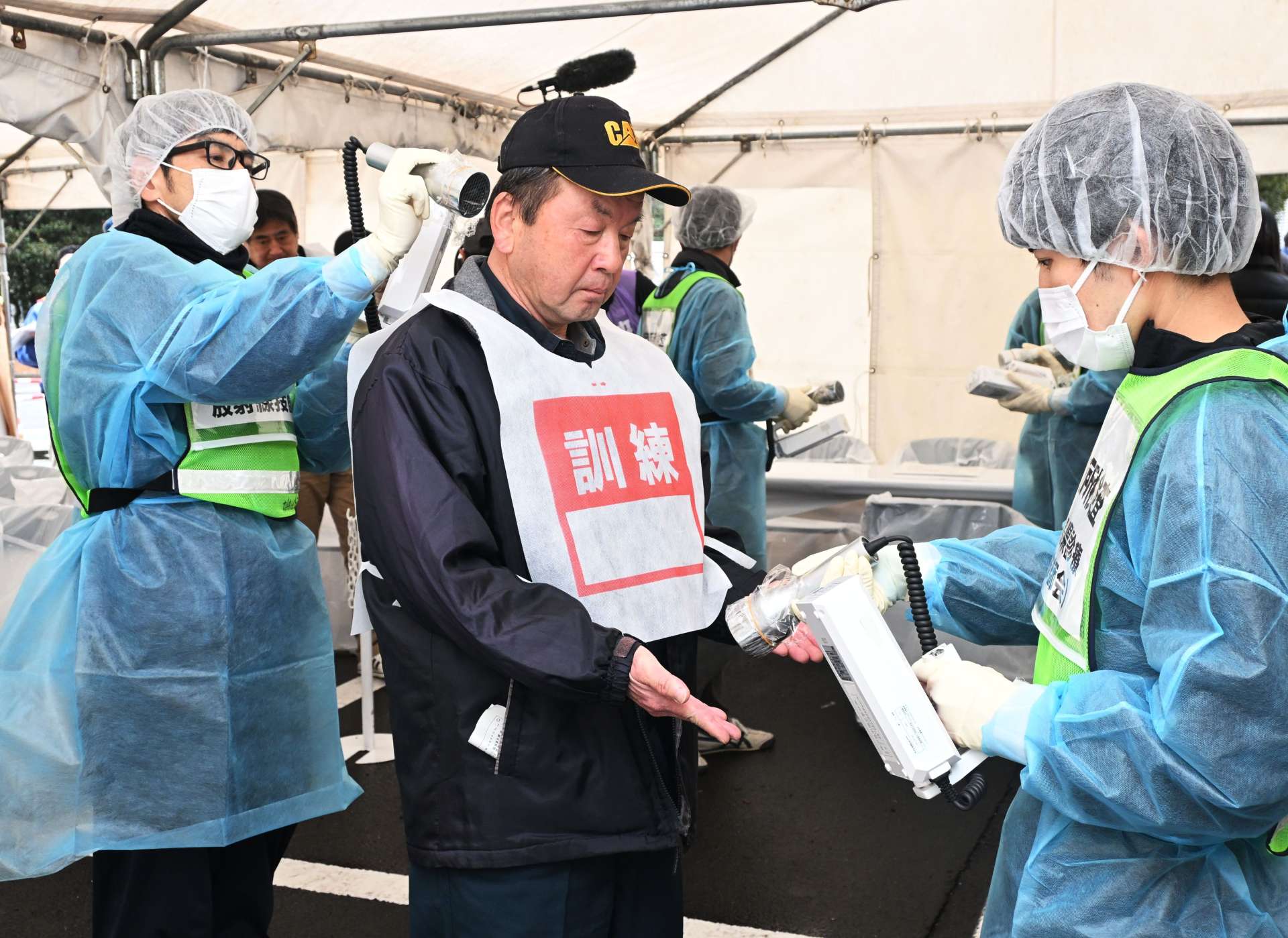 放射性物質が付着していないか検査を受ける訓練参加者（中央）ら＝１６日、姶良市蒲生の県森林技術総合センター