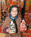 新作の手作りのひな飾りを持つ東郷イツ子さん＝１４日、伊佐市菱刈荒田