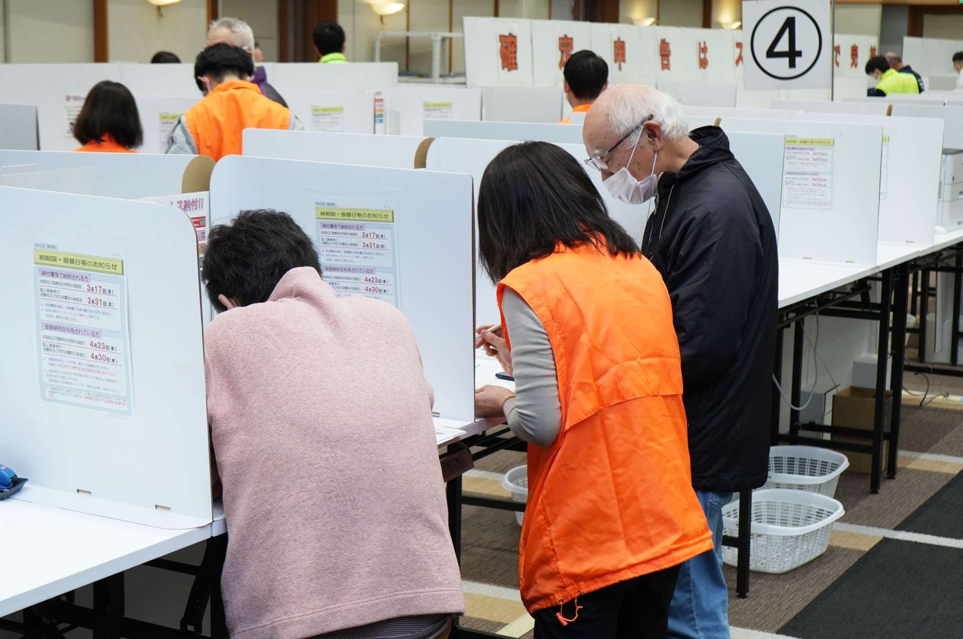 説明を受けながら申告手続きをする来場者ら＝１７日、鹿児島市鴨池新町の県市町村自治会館