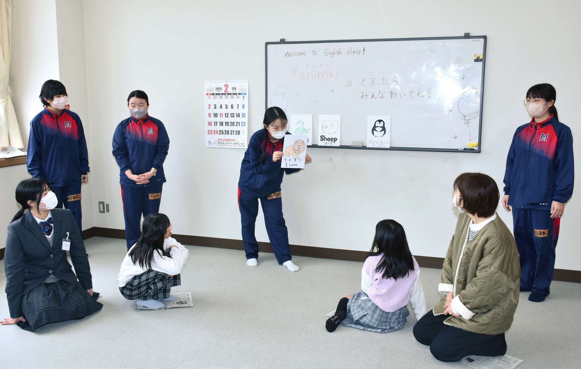 子どもたちと英語でフルーツバスケットをして遊ぶ大口明光学園高校２年のチーム「ライズ」＝１６日、伊佐市の大口元気こころ館