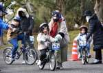 職員の指導のもと自転車の練習をする親子＝南さつま市の吹上浜海浜公園