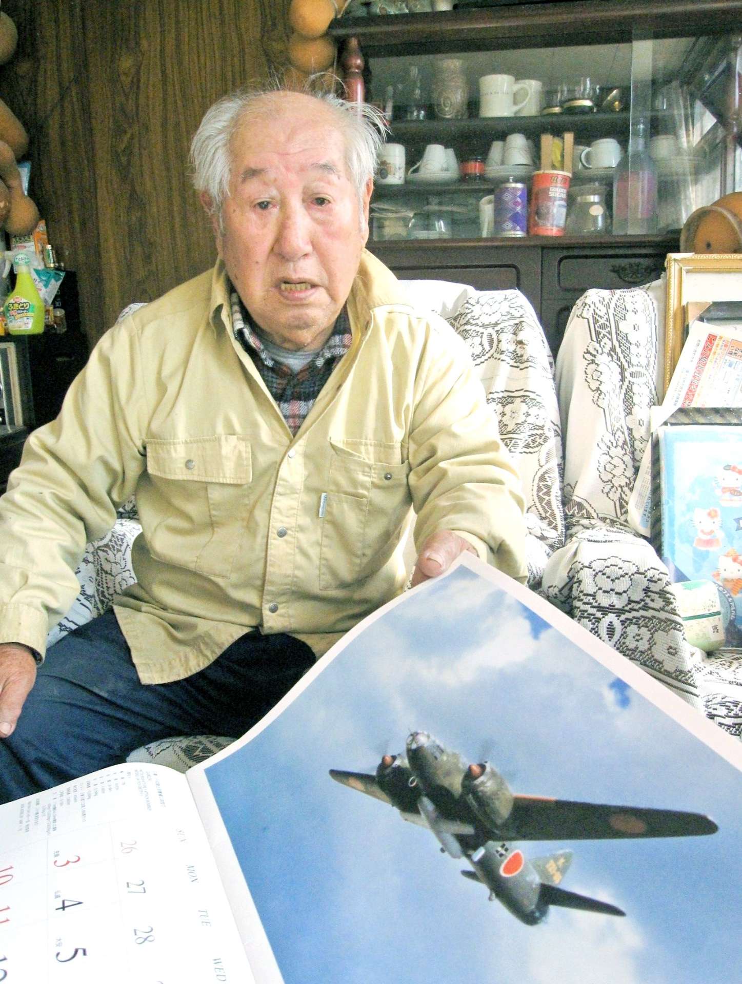戦闘機の載ったカレンダーを見ながら、当時を振り返る宮後正行さん＝日置市吹上