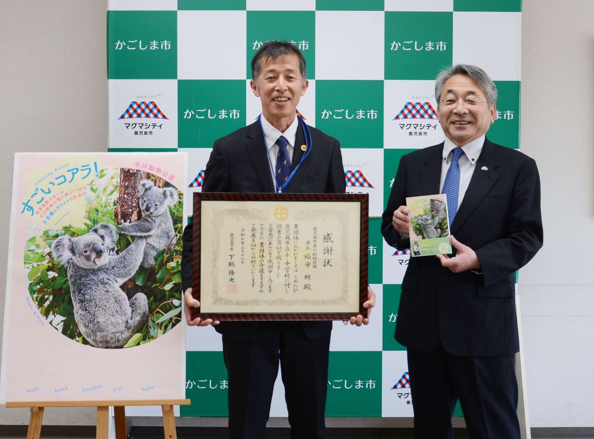 鹿児島市公園公社を代表してコアラの本を贈呈した福守朗平川動物公園長（左）＝【預Ｓ注意】１８日、【預Ｅ注意】市教育総合センター