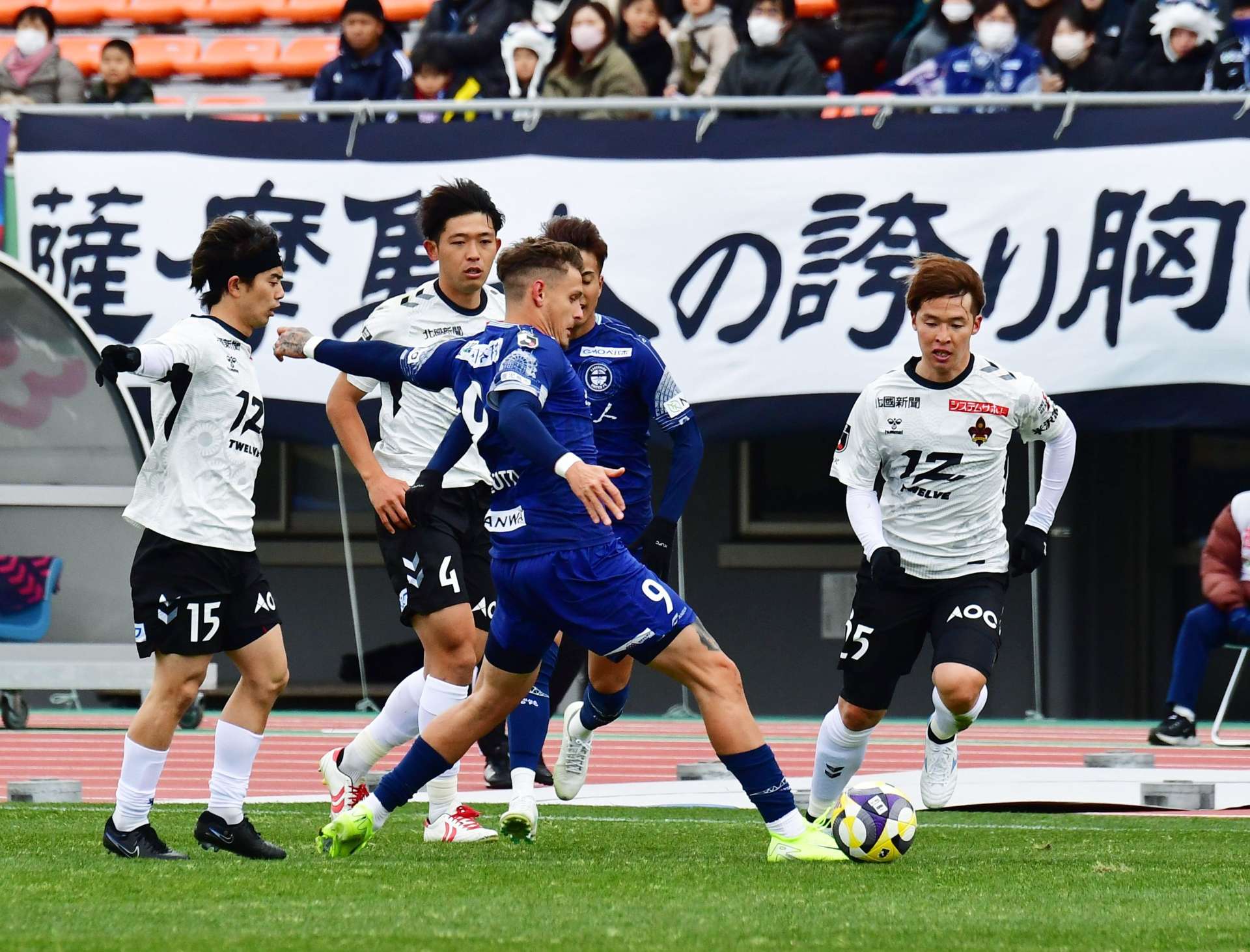 前半、相手と競り合う鹿児島ユナイテッドＦＣのアンジェロッティ（９）＝鹿児島市の白波スタジアム