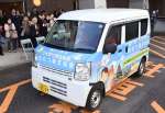出発式で宅配の専用車を見送る関係者＝１９日、南さつま市加世田