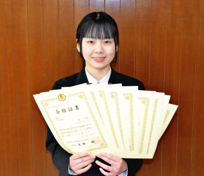 〈関連〉９枚の合格証書を手に笑顔を見せる浜千裕さん＝鹿児島市の明桜館高校