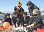 薩摩剣士隼人とともに、桜島沖の調査地点を地図で確認する「チェスト探検隊」の外山雄大隊長（左から２人目）＝鹿児島市桜島赤生原町