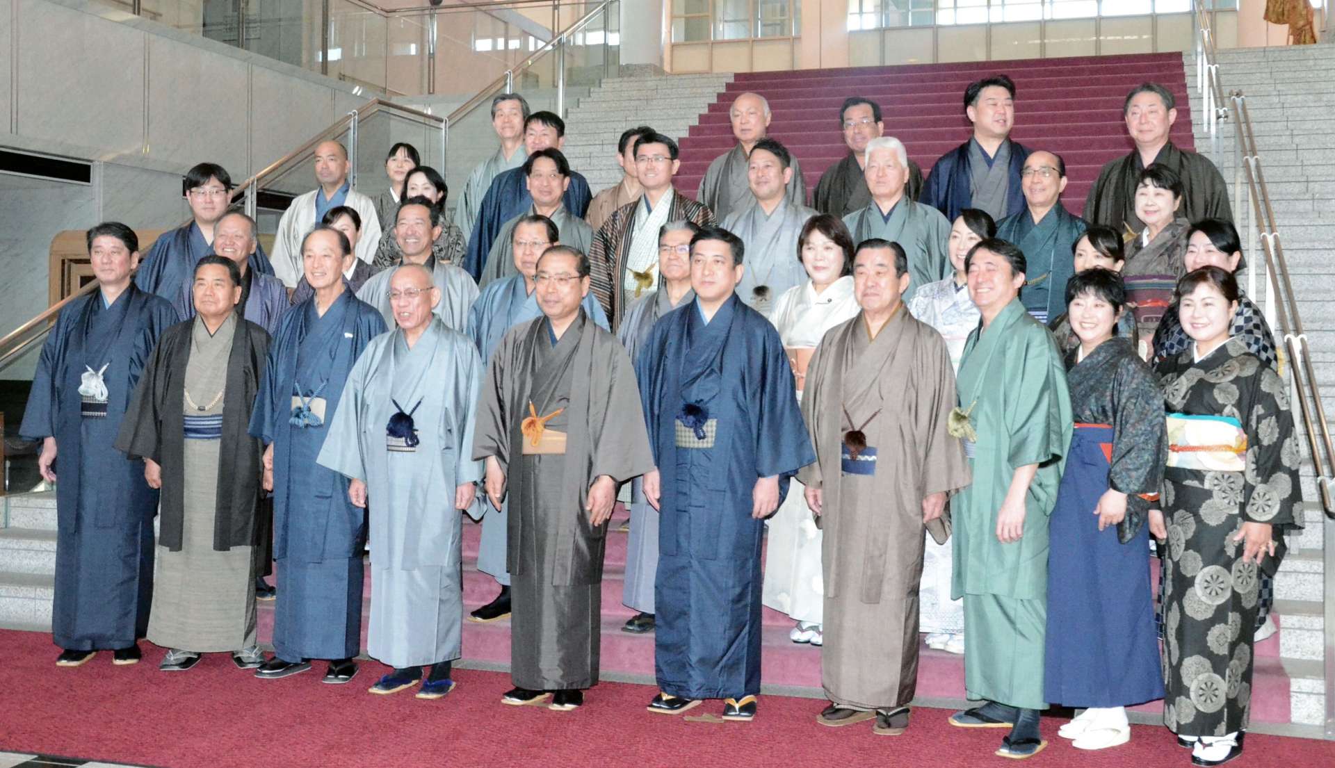 本会議の合間に大島紬姿で記念撮影に臨む塩田康一知事（前列右から５人目）や県議ら＝２５日、県議会