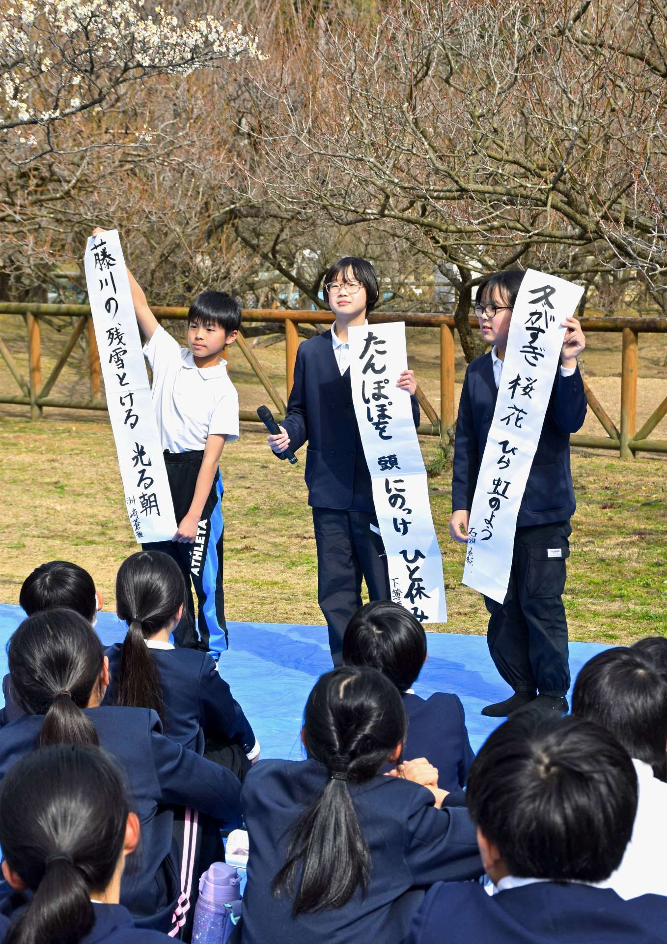 つぼみを付けた臥龍梅に囲まれて俳句を発表する児童たち＝２７日、薩摩川内市の藤川天神