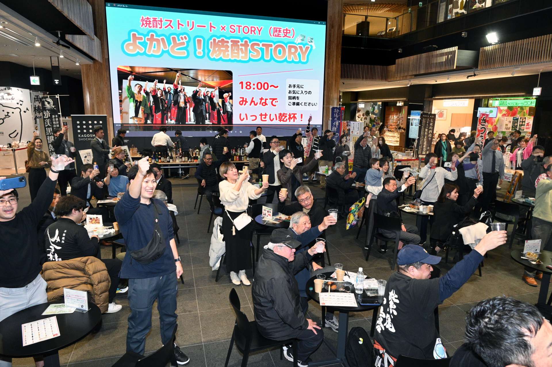 一斉に乾杯するイベント参加者ら＝２８日午後、鹿児島市のよかど鹿児島